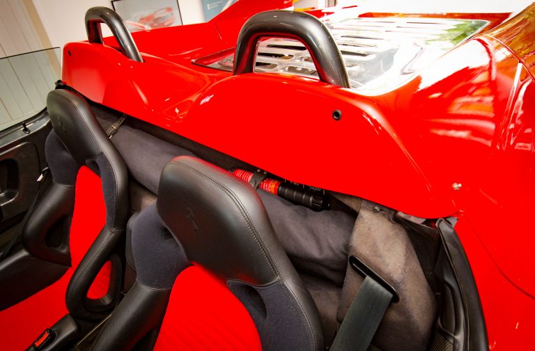 Compact Fire Safety Stick stored behind racing seats in a high-performance sports car interior, demonstrating discreet and residue-free fire protection for valuable vehicles.