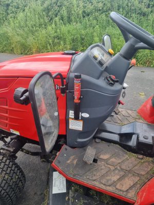 Compact Fire Safety Stick mounted on the dashboard console of a red utility tractor, showing quick and easy access for the operator.